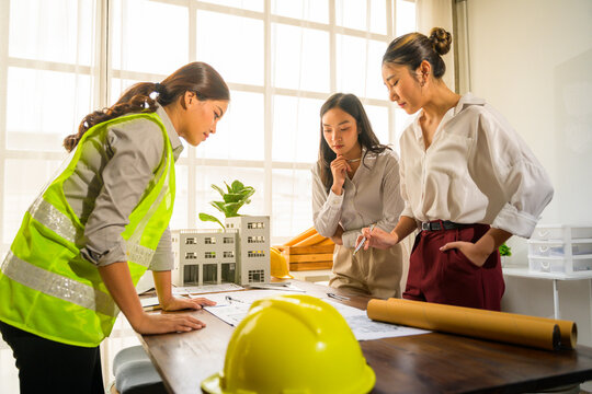 Architects and engineer reviewing blueprints and scale model building