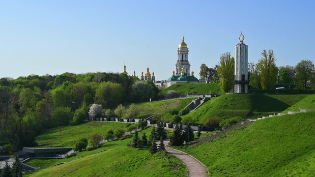 Historic Kyiv Pechersk Lavra monastery and Holodomor memorial overlooking grassy landscape, highlighting cultural heritage against pristine skyline