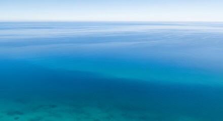 Obraz premium Tranquil aerial view of clear blue ocean water with subtle surface ripples extending to the horizon.