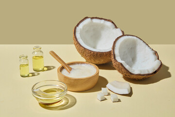Coconuts, golden oil bowl, and oil bottles styled together on beige background. The photo suggests coconut as a versatile ingredient used in luxury natural care products. Space for design