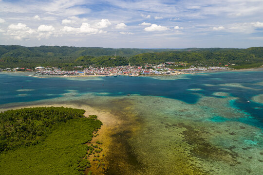 Scenic aerial drone panorama picture of Dapa in Siargao, Surigao del Norte, Mindanao Philippines with reef, corals and water in the foreground