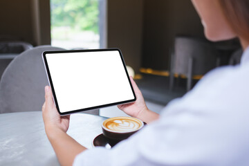 Mockup image of a woman holding digital tablet with blank white desktop screen in cafe