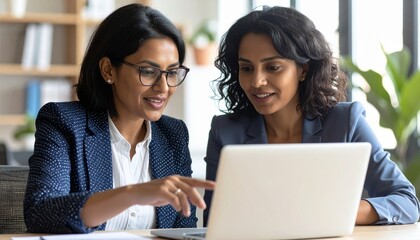 Close up confident Indian businesswoman mentor teaching African American intern. Using laptop, pointing at computer screen. Helping with corporate software. Detailed high quality image. 