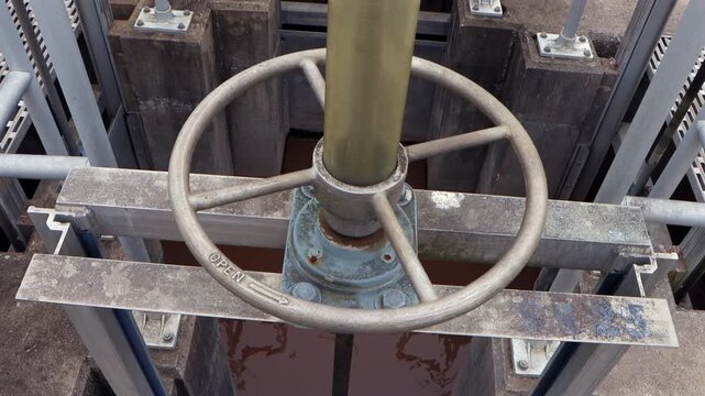 A close-up of a fluid valve handle in an aeration system as the camera tilts upward, revealing industrial mechanism and threaded shaft.