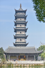 Traditional Chinese Pagoda with Multi-Tiered Structure and Adjacent Hall by a Waterbody