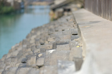 Stone blocks lining a waterfront, with a calm river in the background