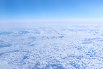 Expansive aerial view of white fluffy clouds with blue sky background in daylight.