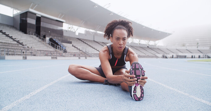 Stretching, sports and woman on track in stadium to start running, exercise and marathon training. Athlete, fitness and person with leg warm up for workout, race competition and challenge outdoor - Powered by Adobe