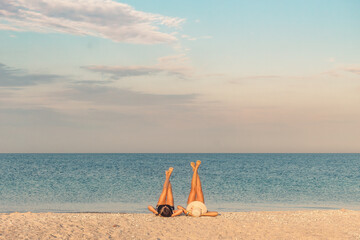 Two women relaxing with legs up on beach