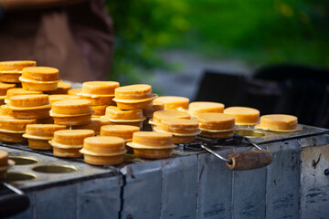 a vendor in the process of making hot and steaming wheel cakes