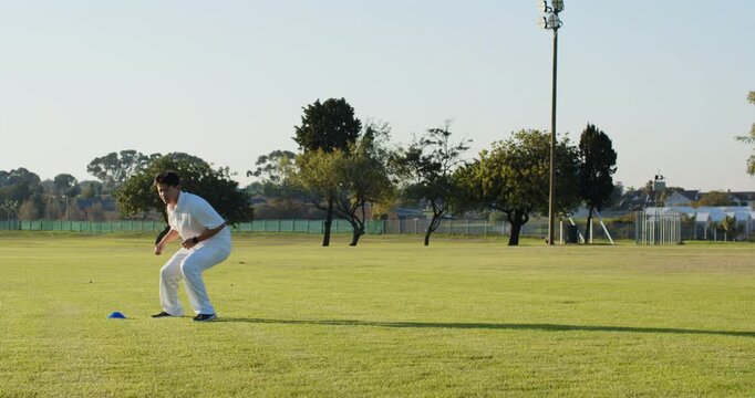 On coach cue diverse male teammates warming up side shuffle around blue cone on grassy field