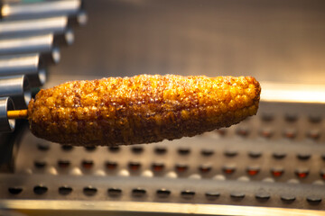 the process of corn being grilled on a barbecue rack