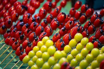 several colorful tanghulu are neatly arranged on a wooden stall