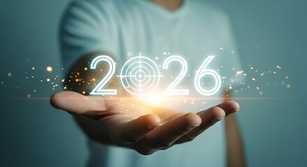 Man holding the year 2026 illuminated with digital particles, representing future planning, goals, and technological advancement
