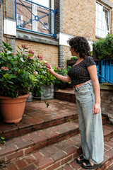 Young woman touching flowers in a brick patio garden