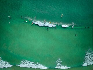 The wave creates a white foamy line contrasting against the clear water, while the surfers are...