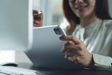 Businesswoman working on computer and using digital tablet at office for video conference, online meeting. Happy business woman having a discussion with colleagues via online meeting app