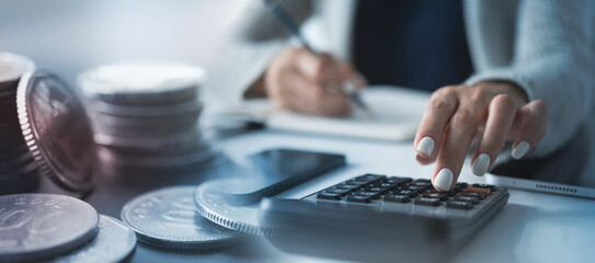 Business, finance and investment, budget planning concept. Accountant using calculator with coins, doing finance and budgeting, banking, tax calculation, financial background