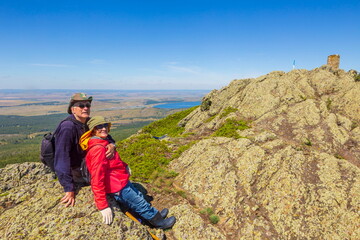 happy mature married couple traveling through the Ural mountains on a summer day