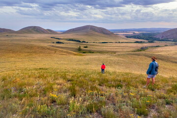 tourists walk along the ridge of karamuruntau against the backdrop of andreevskie cones in the...