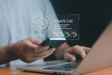Man using smartphone and laptop with ISO checklist icons, symbolizing quality standards,...