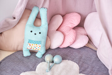 Cozy children s playroom with stuffed toys and cushions in soft pastel colors.