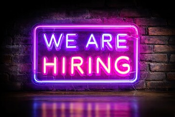 Neon sign on brick wall announces job openings
