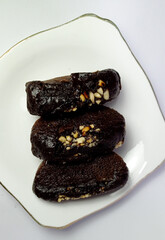 Dark chocolate dates with chopped nuts on elegant white plate
