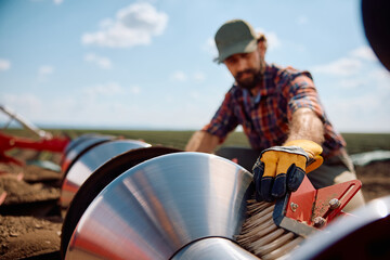 Close up of agronomist setting up disc harrows on a tractor while plowing the land. © Drazen