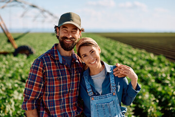 Happy couple of farmers working in the field and looking at camera.
