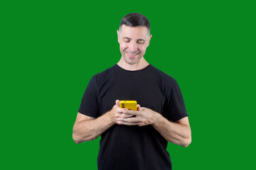 A man is smiling while holding a cell phone. Green isolated background