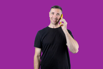 A man is talking on a cell phone while smiling. Purple isolated background