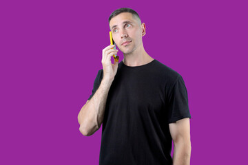 A man is talking on a cell phone while looking at the camera. Purple isolated background