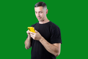 A man is holding a yellow phone and smiling. Green isolated background