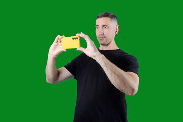 A man is taking a picture with his cell phone. Green isolated background