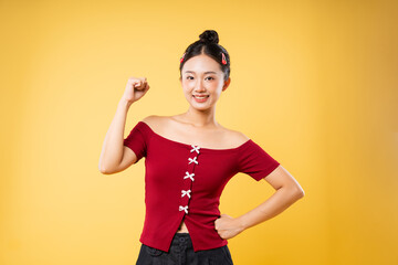 Confident young woman in red top smiles with fist raised symbolizing strength and positivity