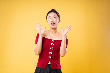Surprised woman in stylish red top with matching hair clips against a vivid yellow backdrop