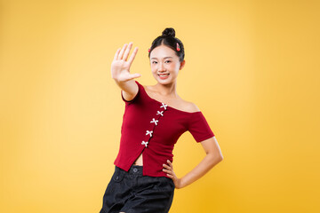 Smiling woman in red top with hand outstretched against a bright yellow studio background