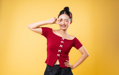 Young woman posing with peace sign in front of yellow backdrop cheerful beauty concept