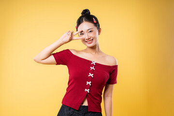 Smiling woman in off-shoulder red top posing with a peace sign against a yellow background