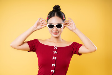 Stylish woman with white frame glasses cherry hair clips and a charming smile on a yellow background