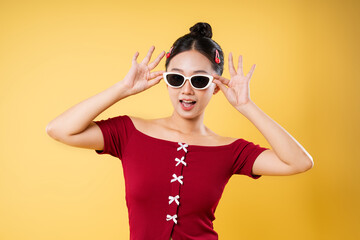 Stylish woman with sunglasses and hair clips poses against a vibrant yellow background