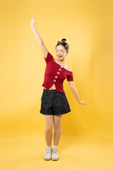 Expressive young woman posing dynamically in casual summer attire against a vibrant yellow backdrop