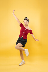 A young woman in vintage-inspired clothing striking a playful pose against a cheerful yellow...
