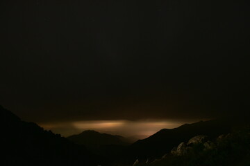 Dramatic Silhouette of Mountains at Dusk with a Glimmer of Light on the Horizon