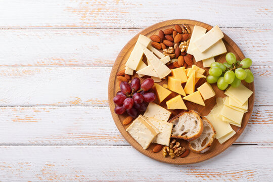 A delicious cheese board with grapes, nuts, and bread slices on a wooden platter, overhead view