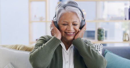 Senior woman, happy and headphones on sofa for streaming podcast, radio app or music. Retirement,...