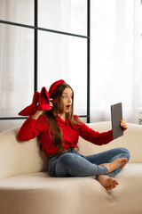 Surprised teen girl holding red shoes making video call. Concept of lifestyle, use digital...