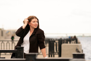Woman in brown suit standing confidently by waterfront outdoors. Natural feel with soft light....