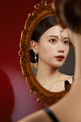 Elegant woman with earrings reflected in a vintage mirror.